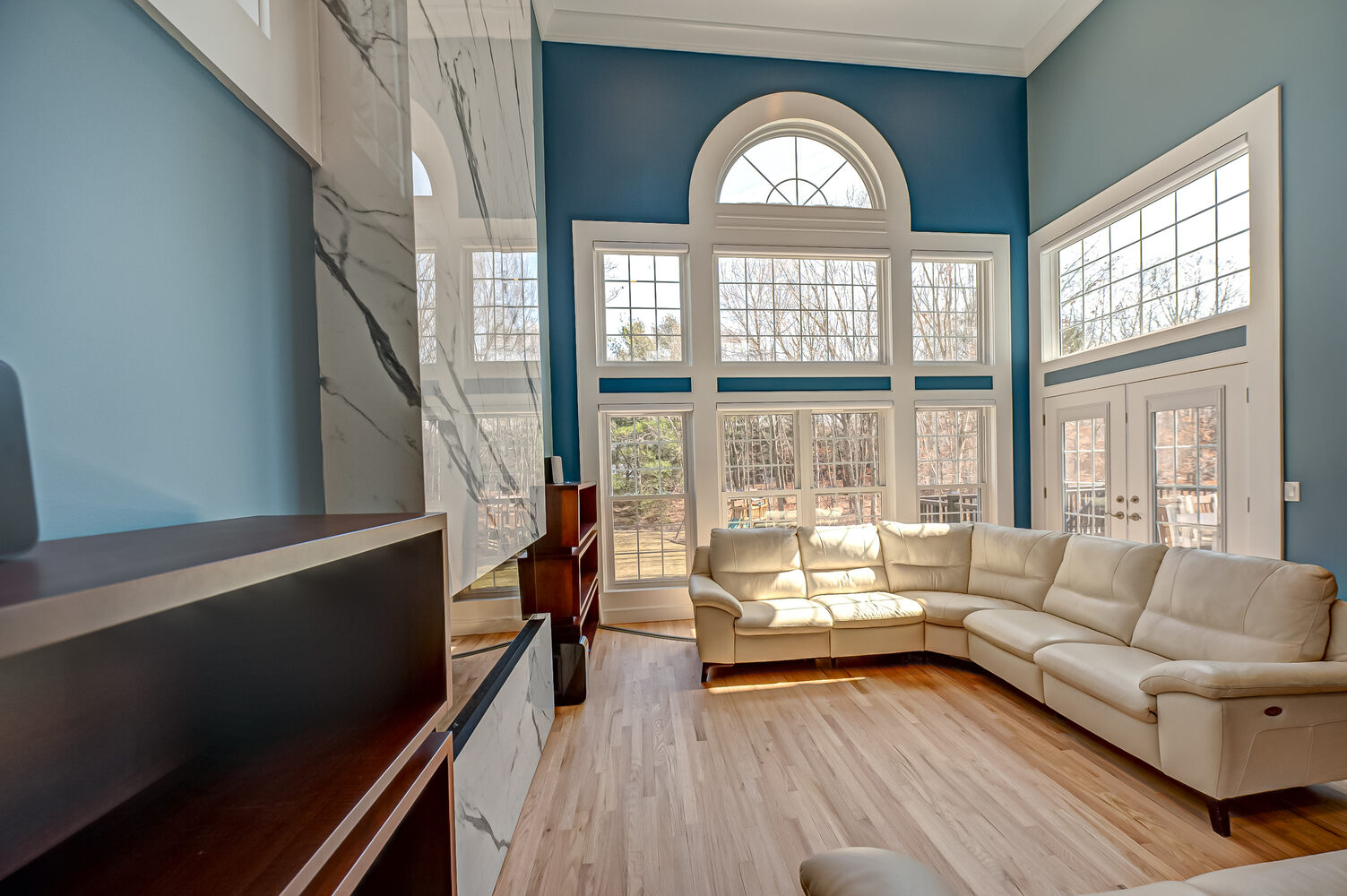 Sophisticated great room design featuring classic arched windows and stone-style fireplace in Suffolk County, NY
