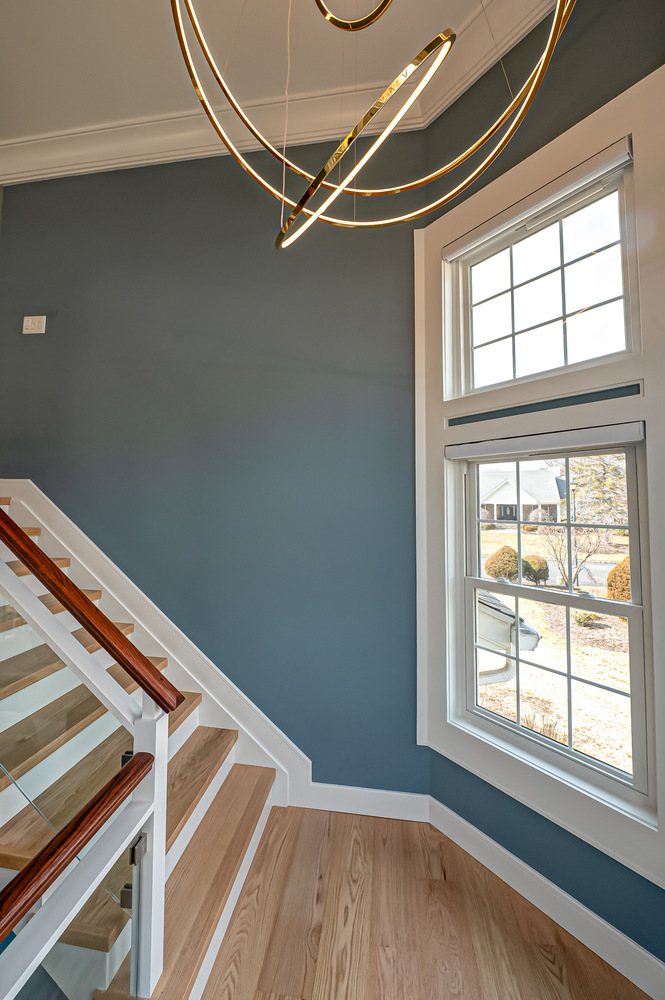 Staircase featuring blue walls and wood handrails in Three Villages, NY custom home by Long Island Creative Contracting, Inc