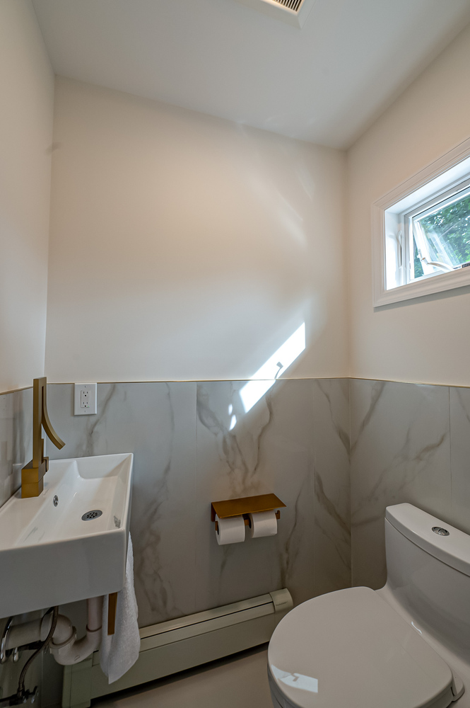 Bright bathroom corner with natural light and modern finishes by Long Island Creative Contracting in Remsenberg, NY