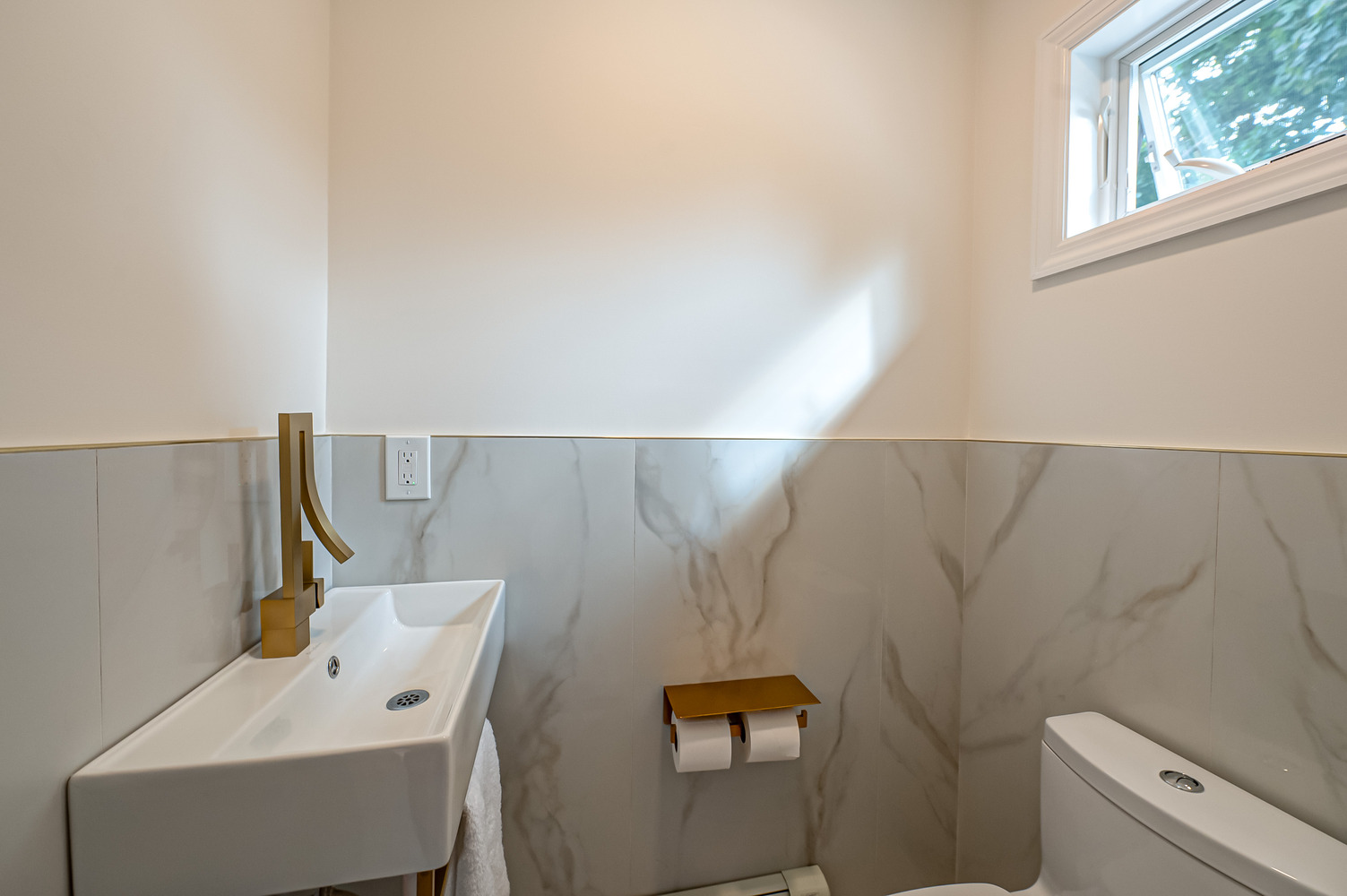Custom powder room with tall gold faucet and marble wall detail by Long Island Creative Contracting in Port Jefferson, NY