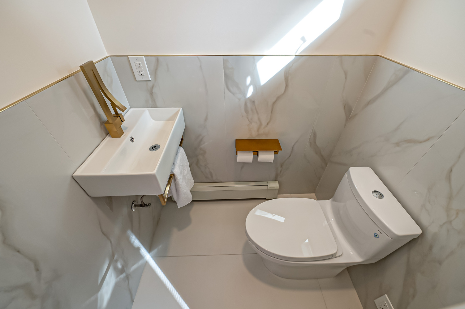 Modern powder room with gold fixtures and wall-mounted sink in a custom home by Long Island Creative Contracting in Miller Place, NY