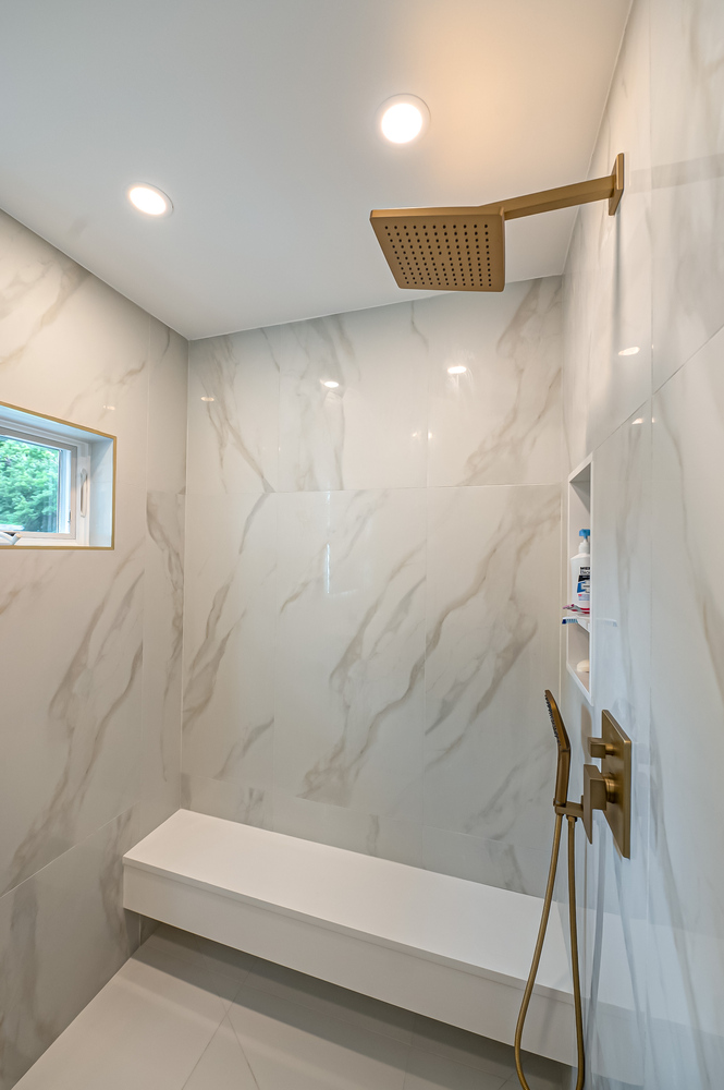 Spa-style shower with marble walls and rain showerhead in a custom home by Long Island Creative Contracting in Northport, NY
