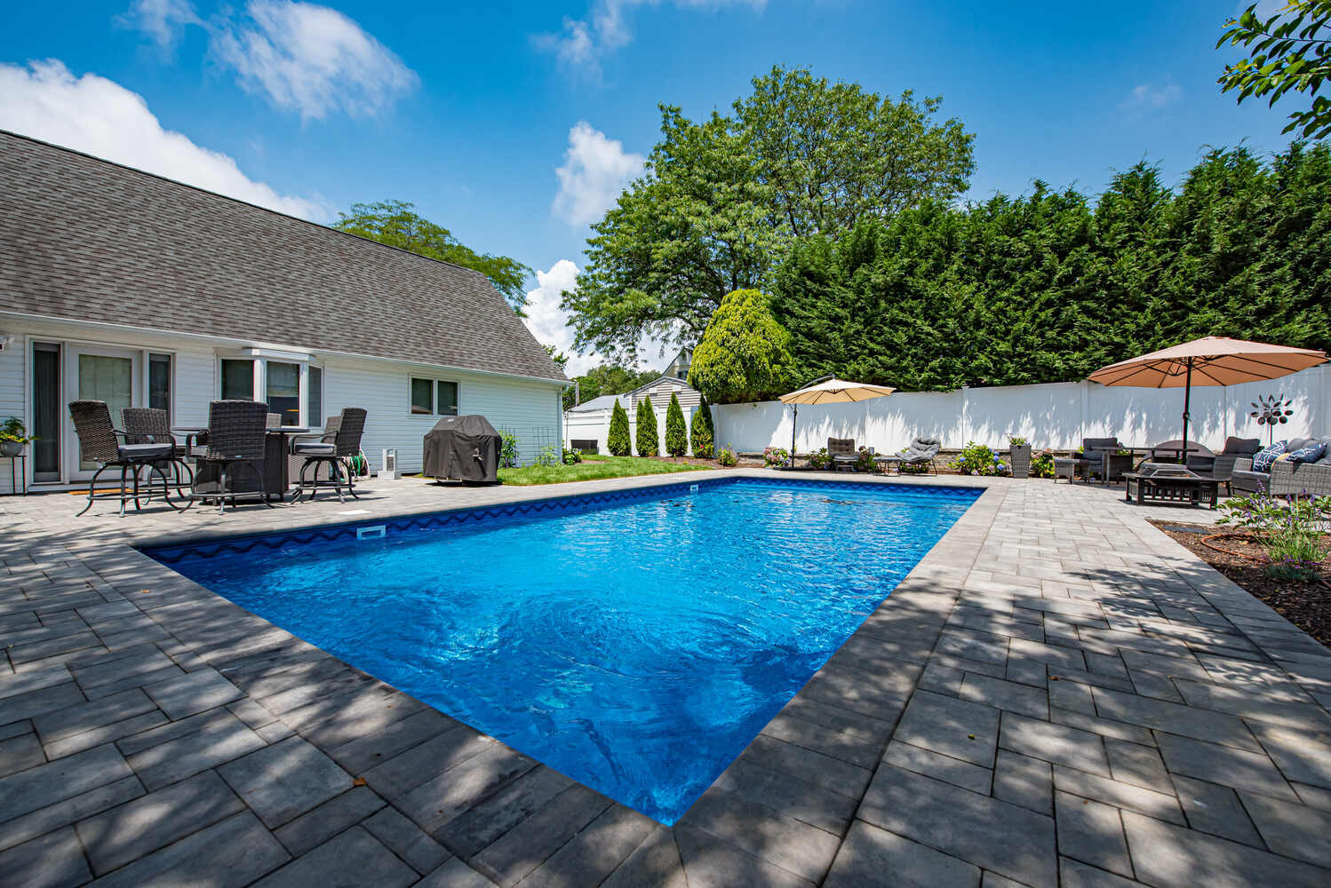 Backyard view of custom pool and home exterior designed by Long Island Creative Contracting in Miller Place, NY