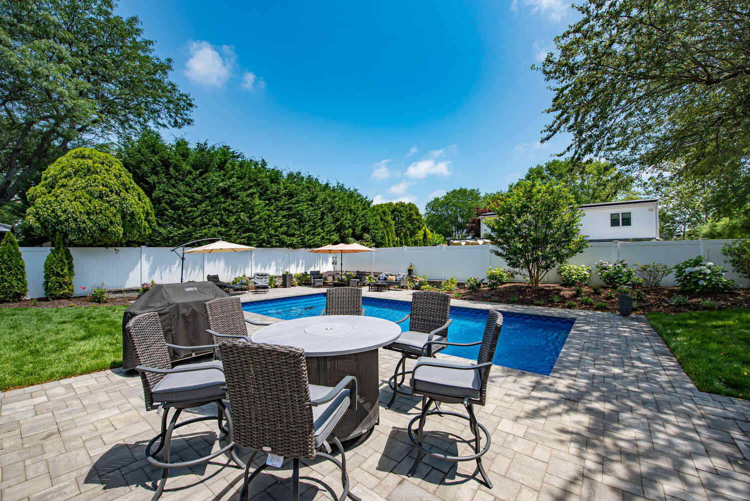 Circular outdoor dining set near custom inground pool built by Long Island Creative Contracting in Miller Place, NY