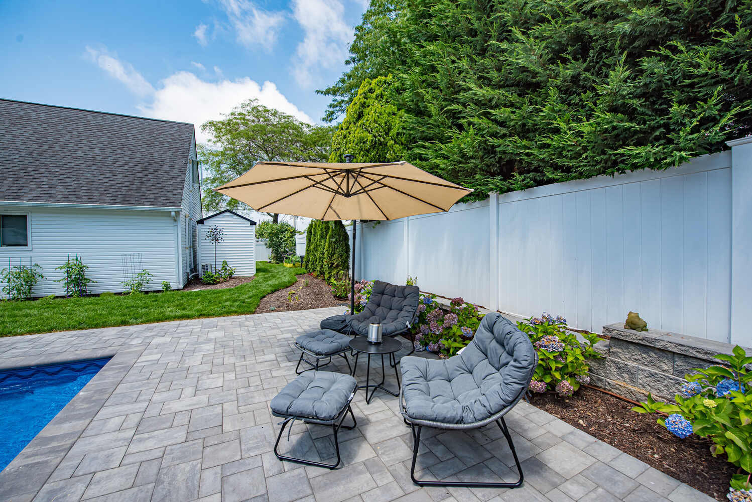 Custom backyard seating area with patio and umbrella installed by Long Island Creative Contracting in Miller Place, NY