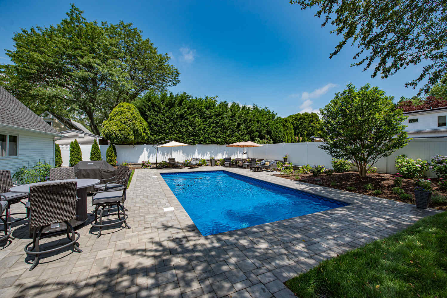 Custom pool installation with large stone pavers and umbrellas in Miller Place, NY by Long Island Creative Contracting