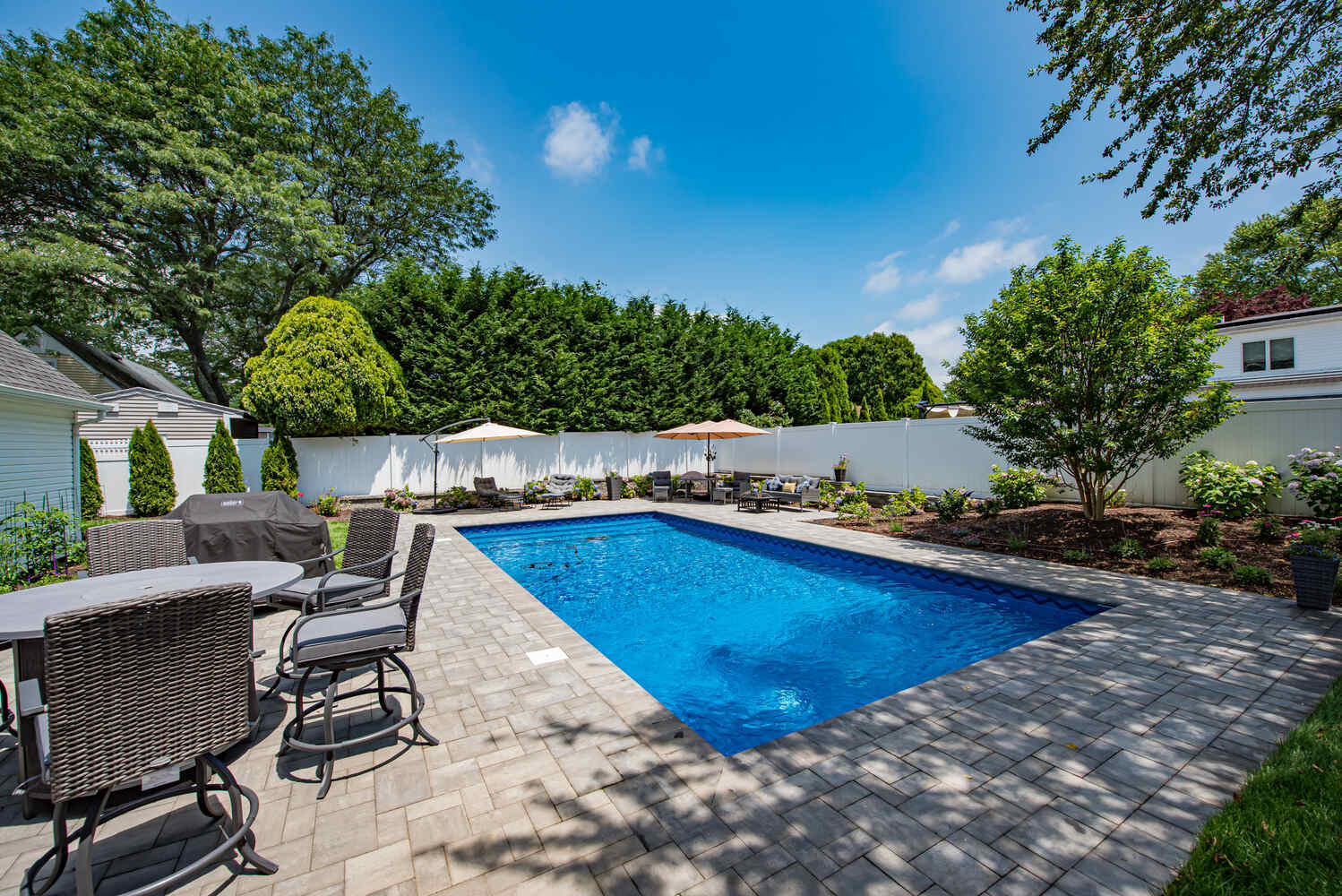 Custom pool with light stone paver surround and garden landscaping in Miller Place, NY by Long Island Creative Contracting