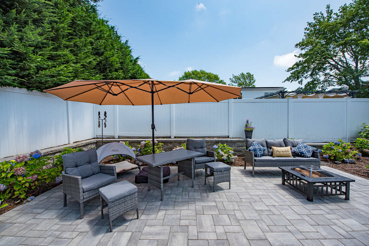 Lounge area with umbrella and patio furniture in custom Suffolk County backyard by Long Island Creative Contracting, Inc