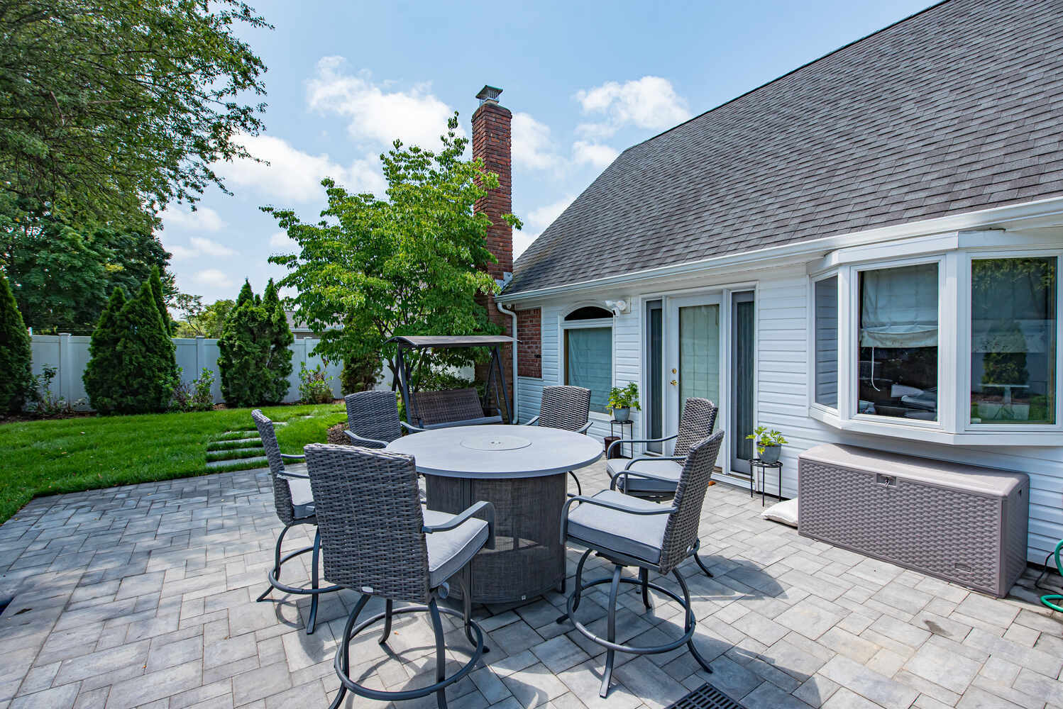 Outdoor round dining table on paver patio at a Suffolk County custom home by Long Island Creative Contracting