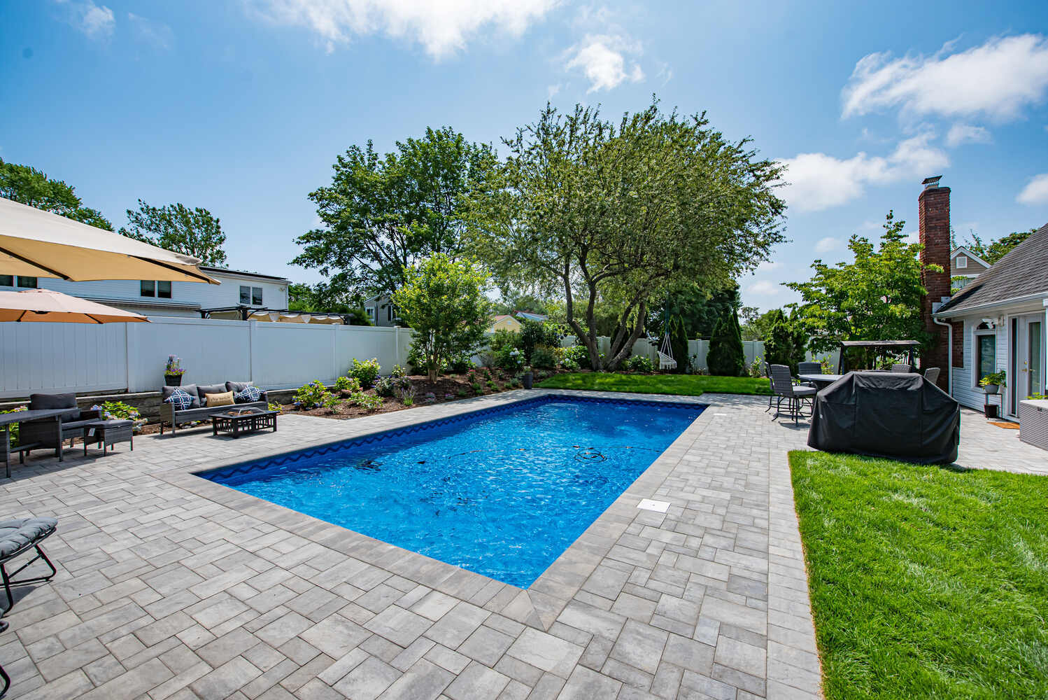 Poolside patio with grill and dining set at a custom Long Island Creative Contracting home in Miller Place, NY
