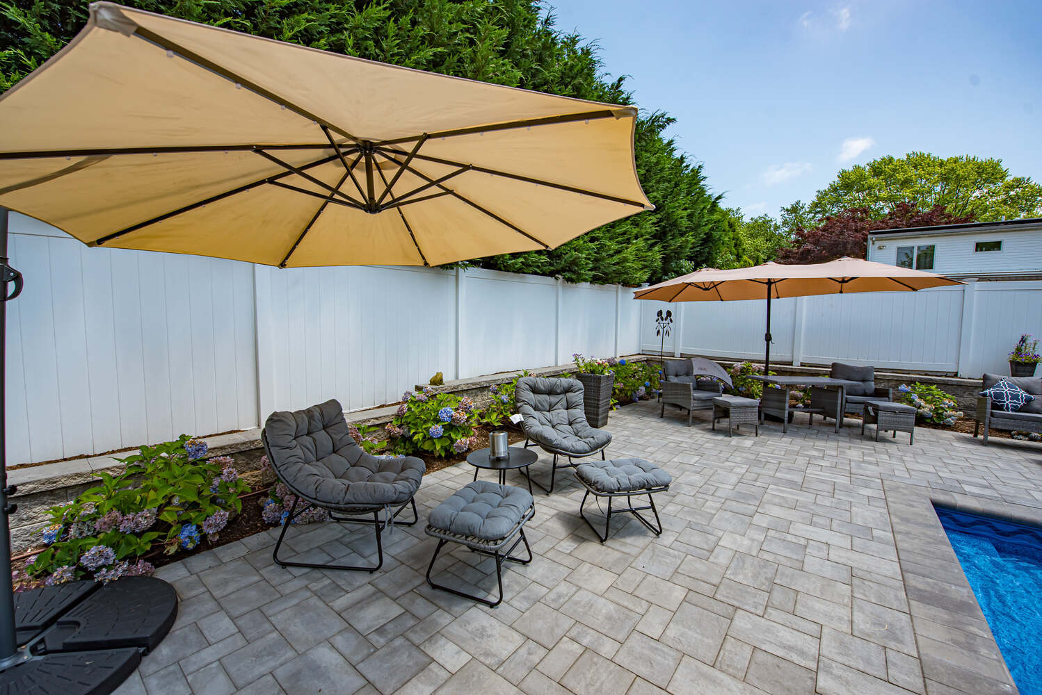 Relaxation space with garden views and umbrella seating at a Suffolk County custom home by Long Island Creative Contracting