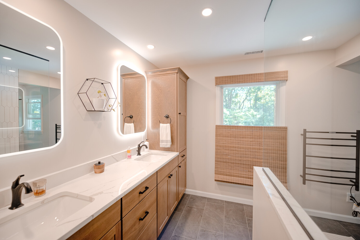 Contemporary double vanity bathroom with wood cabinetry and LED mirrors by Long Island Creative Contracting in Miller Place, NY