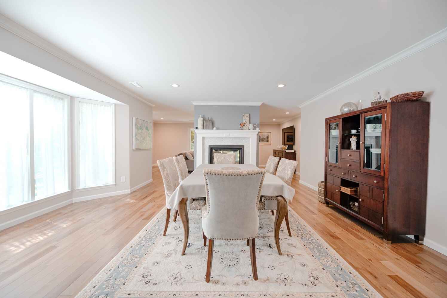 Dining area with fireplace and china cabinet in a custom home in Suffolk County by Long Island Creative Contracting, Inc