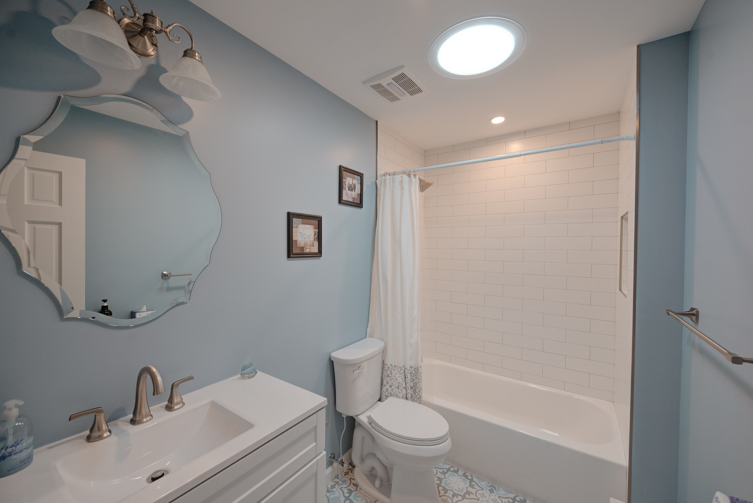 Light blue bathroom with white vanity and tiled shower in a Miller Place custom home by Long Island Creative Contracting