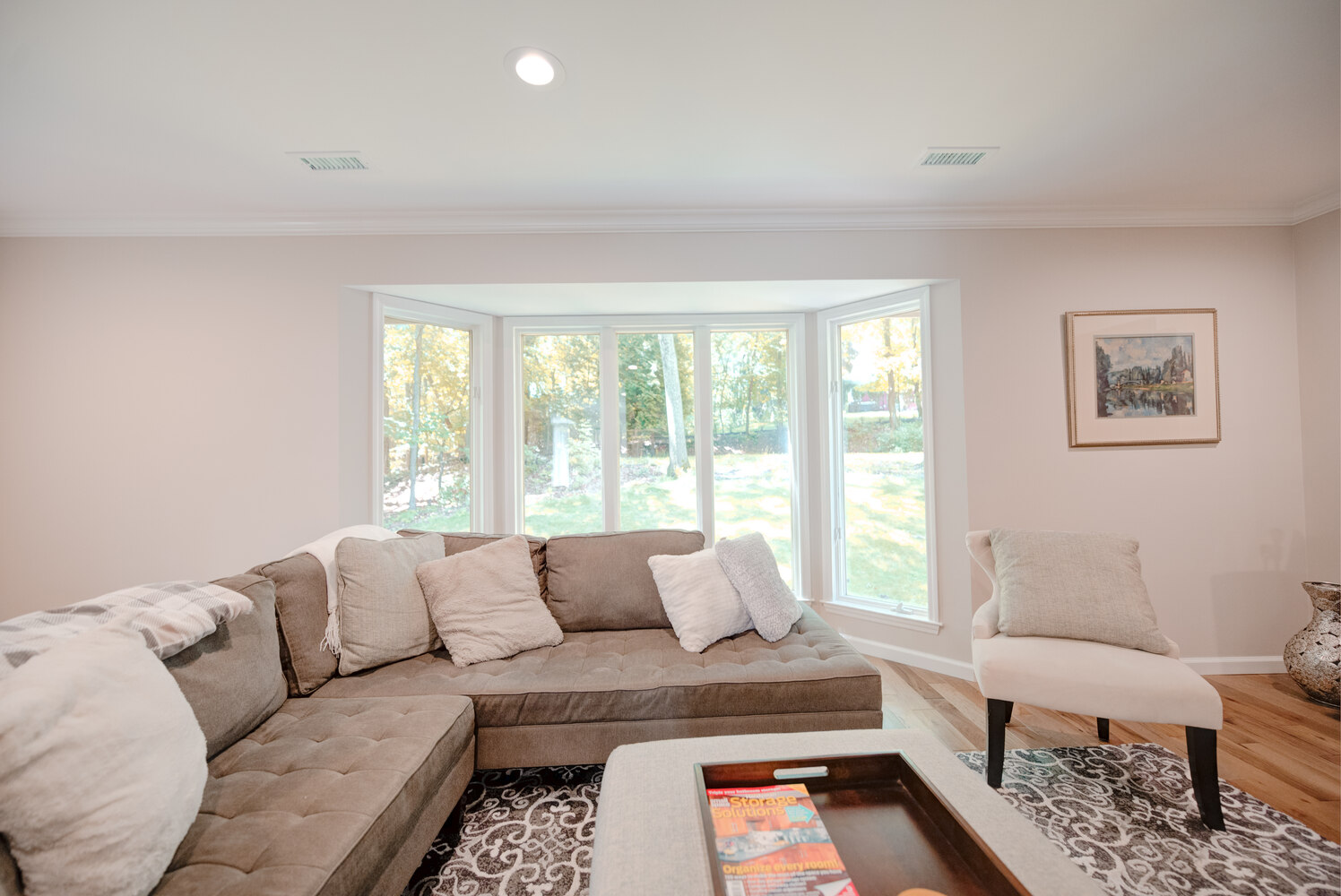 Living room with bay windows and sectional sofa in a Long Island Creative Contracting, Inc. custom home in Setauket, NY