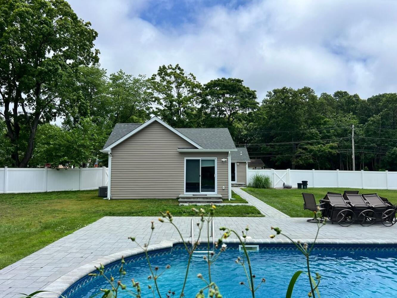 Backyard view of guest house with paver patio and pool in a Suffolk County custom home by Long Island Creative Contracting