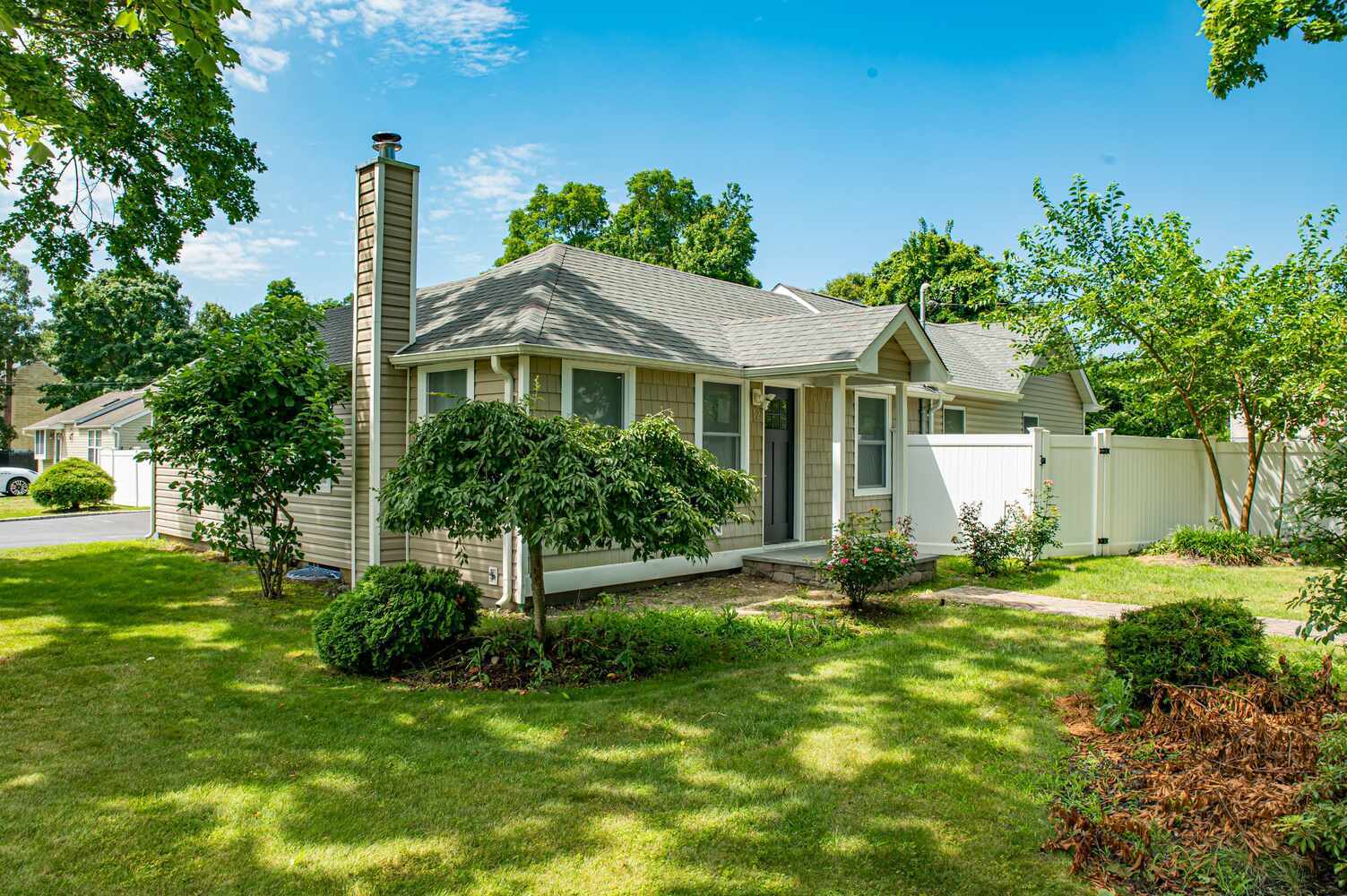 Charming exterior of a single-story home with landscaping by Long Island Creative Contracting in Northport, NY