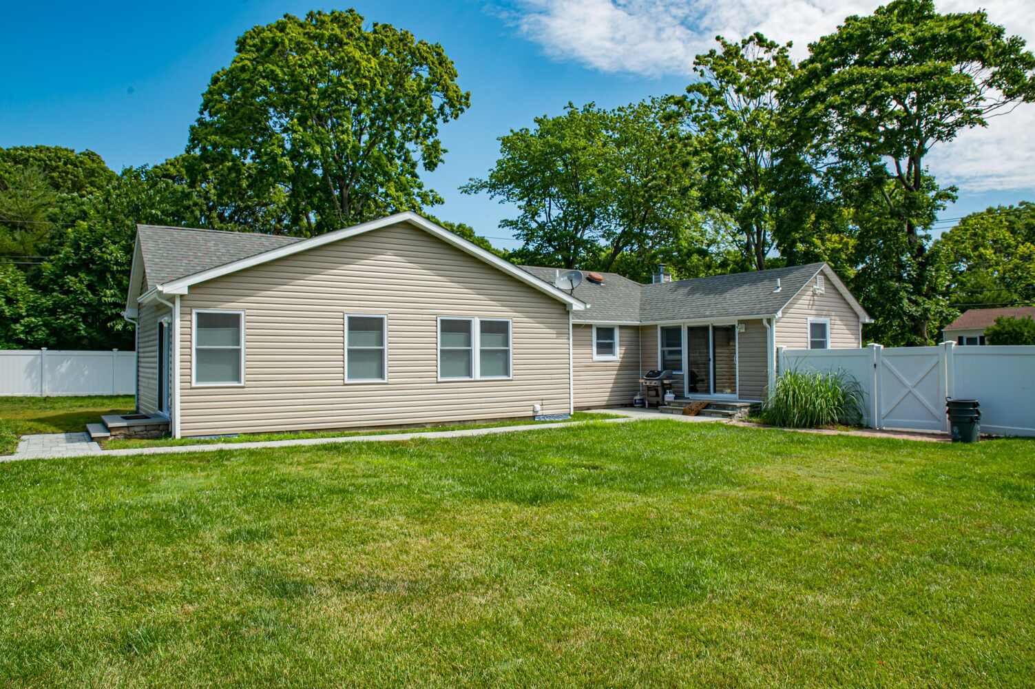 Rear view of custom ranch home with fenced yard by Long Island Creative Contracting in Port Jefferson Station, NY
