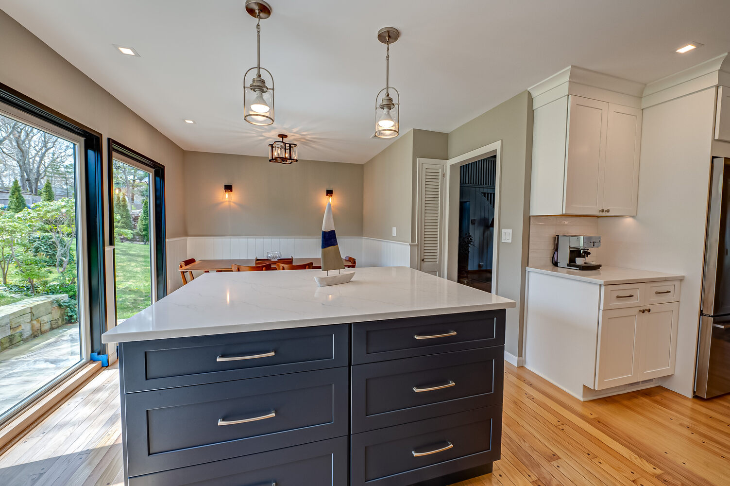 Bright kitchen with island and panoramic windows in Woodbury, NY by Long Island Creative Contracting, Inc
