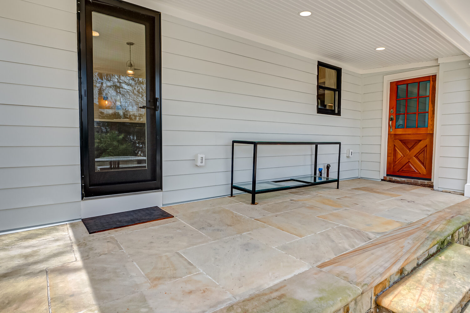 Covered back porch with stonework and new exterior doors in Miller Place, NY by Long Island Creative Contracting, Inc