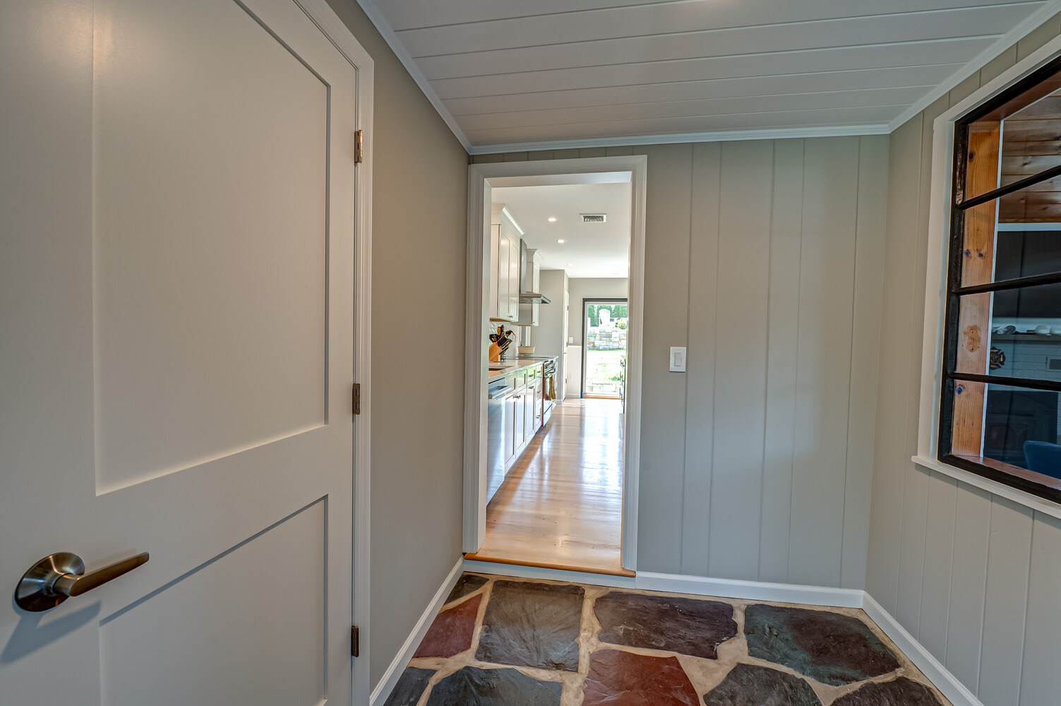 Custom-built entry hall with slate tile and view into open-concept kitchen in Suffolk County