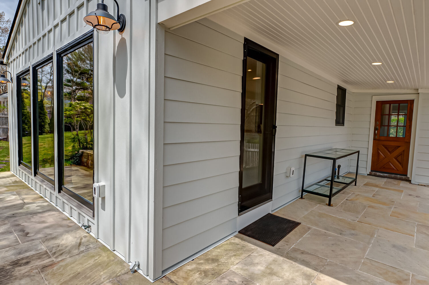 Detailed exterior view of custom home with glass door and covered porch in Miller Place, NY