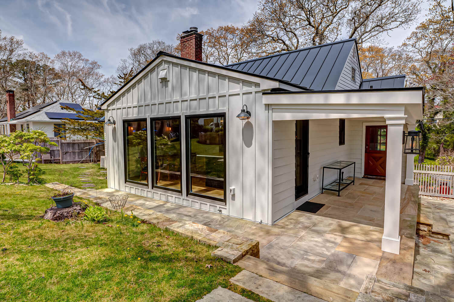 Full view of custom home exterior with large windows and backyard patio in Miller Place, NY
