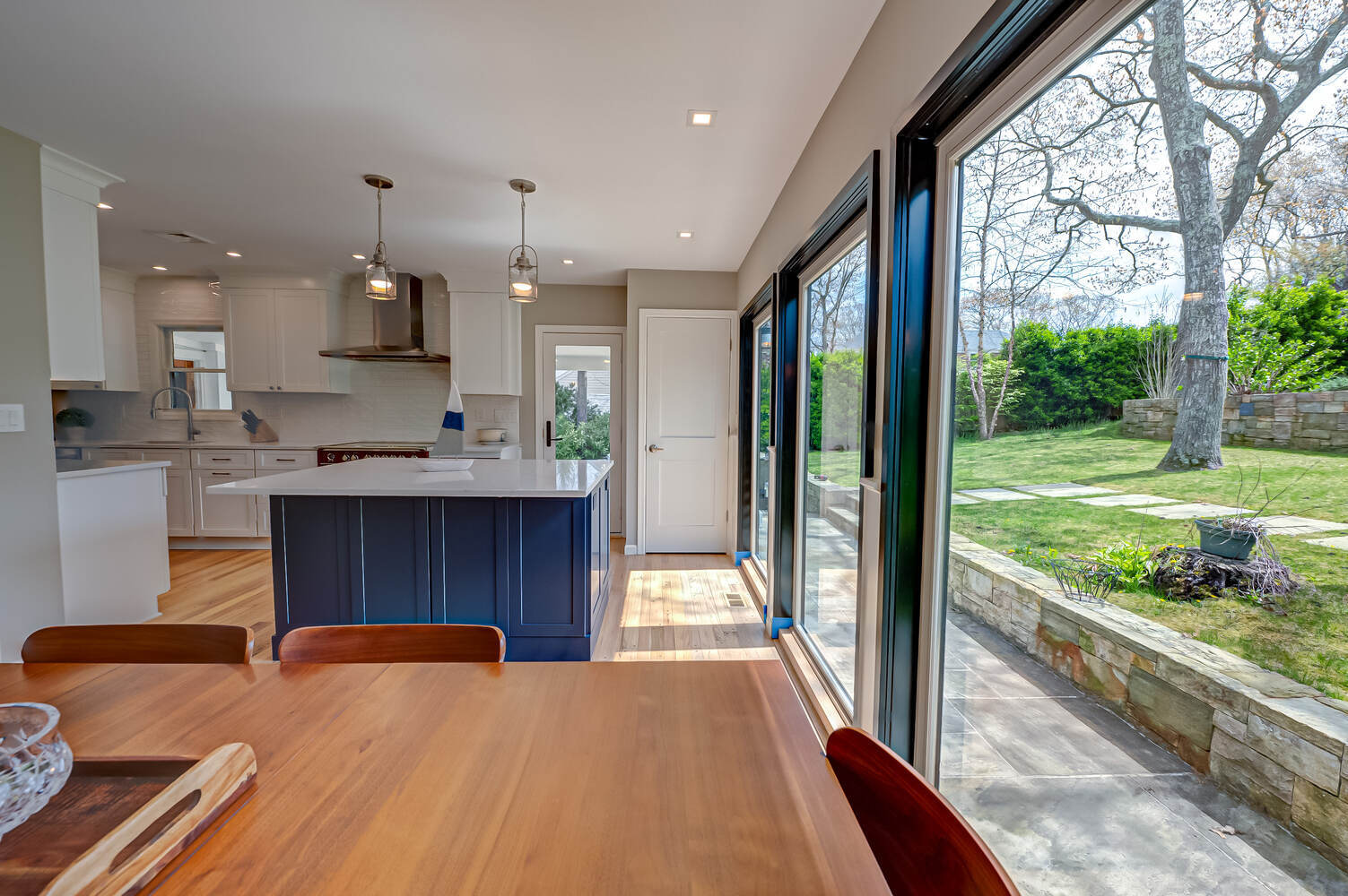 Garden-facing kitchen with dining space and pendant lighting in Remsenberg, NY by Long Island Creative Contracting, Inc