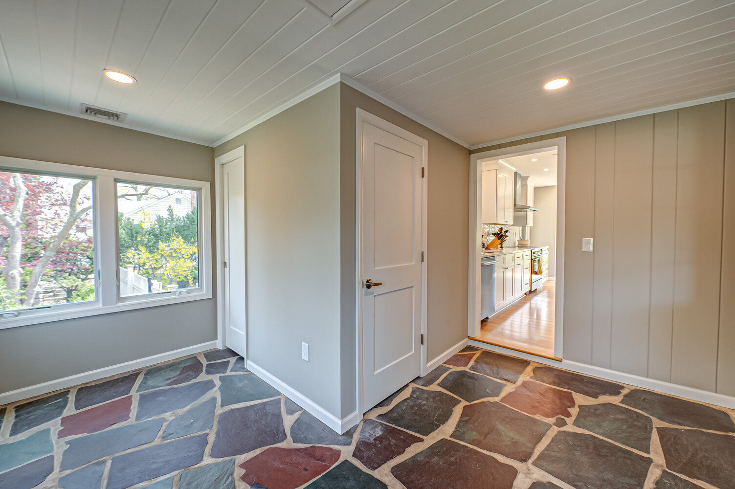 Hallway with natural stone floor leading to white cabinetry kitchen in Suffolk County, NY