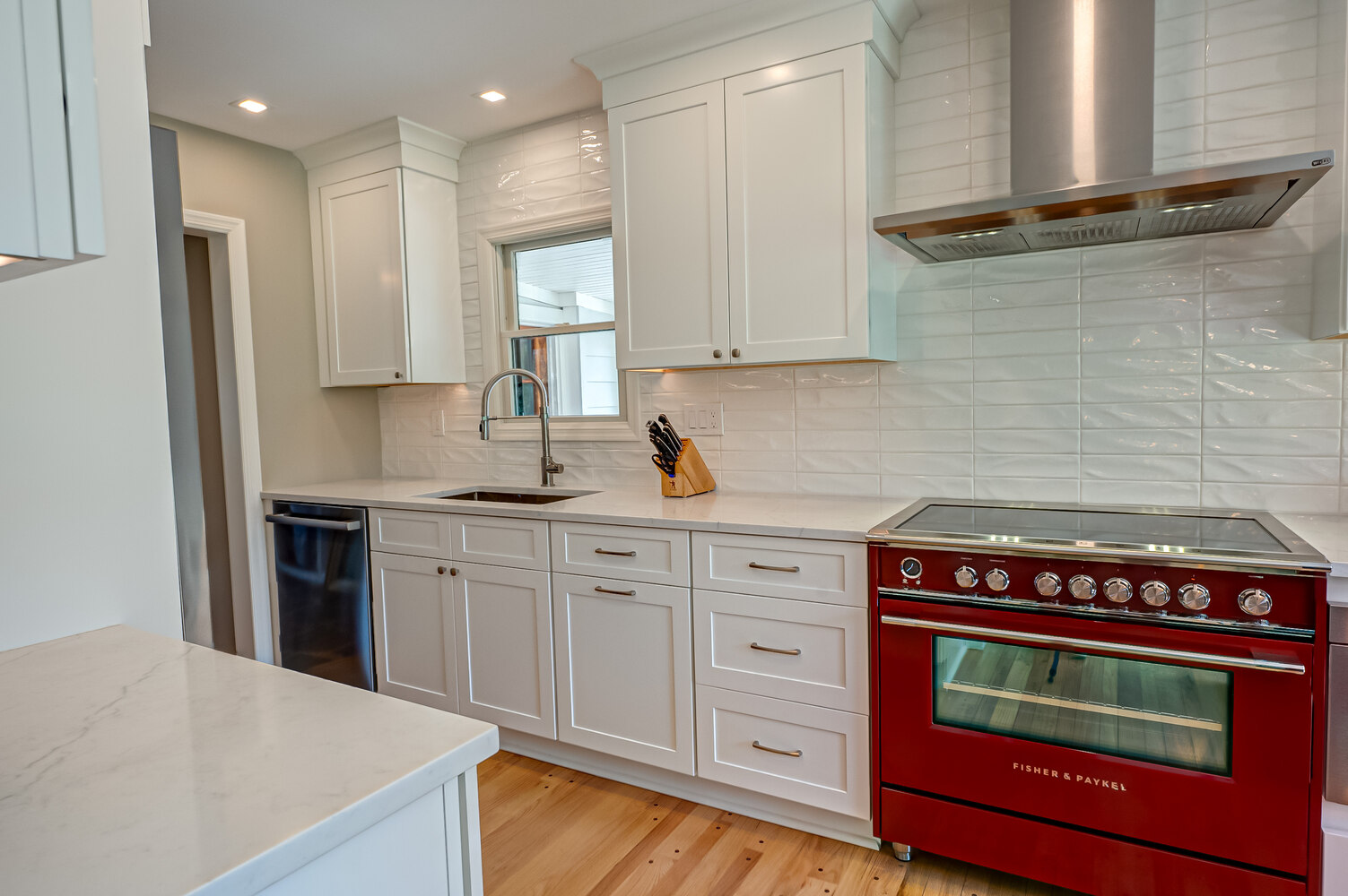 Modern kitchen with red range and white cabinetry in custom home by Long Island Creative Contracting