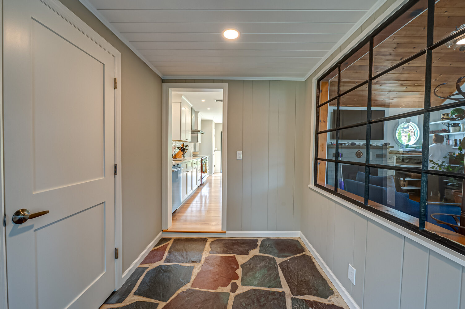 Rustic-modern entryway with wood-accented window and natural stone flooring in Suffolk County custom home