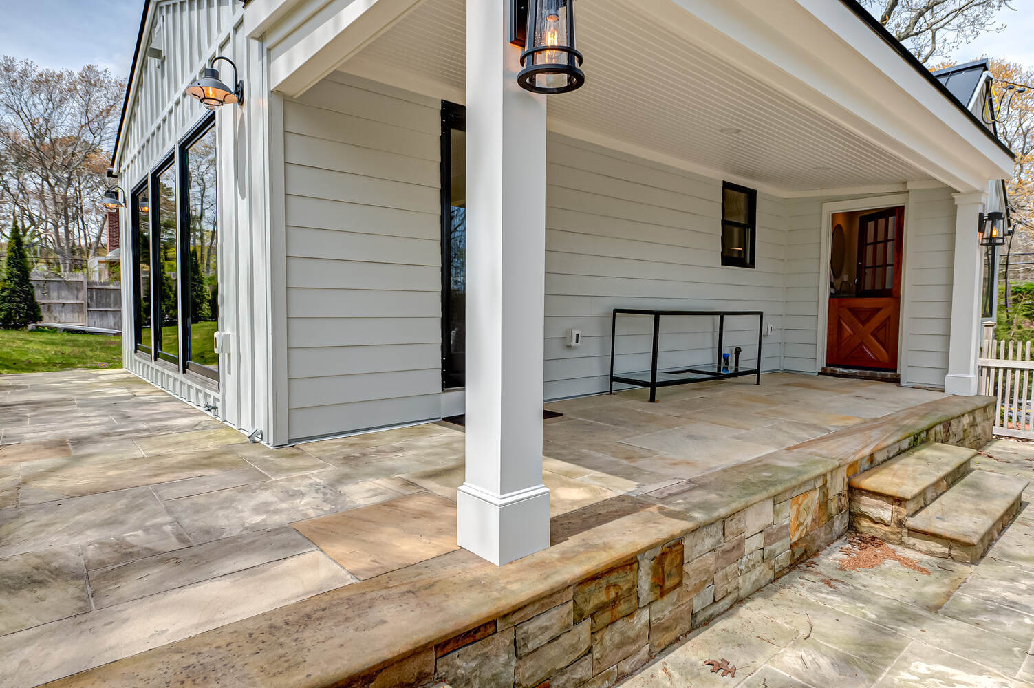 Side view of custom home exterior with stone patio by Long Island Creative Contracting in Miller Place, NY