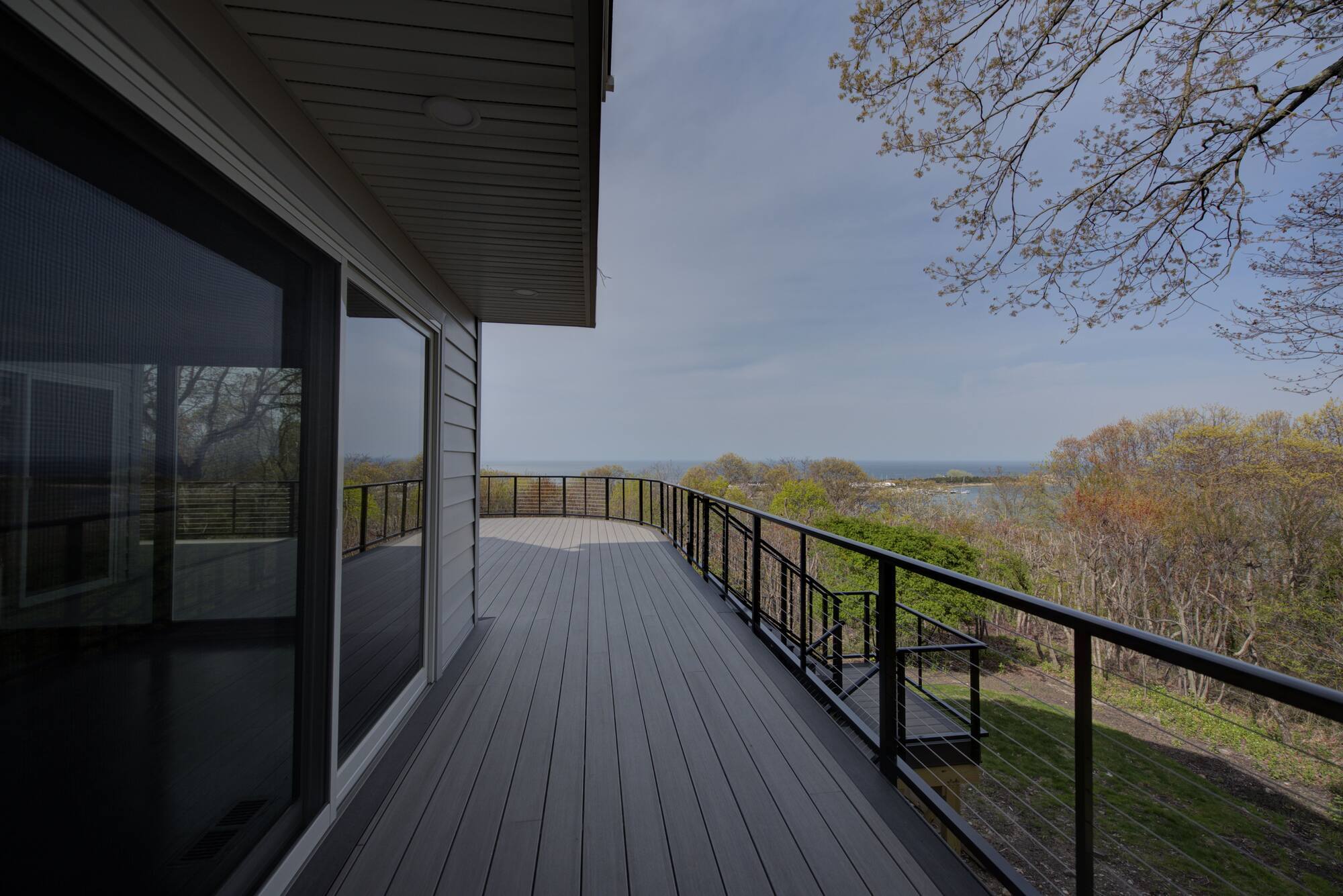 Custom-built deck with black railings and panoramic water views in Suffolk County, NY by Long Island Creative Contracting, Inc