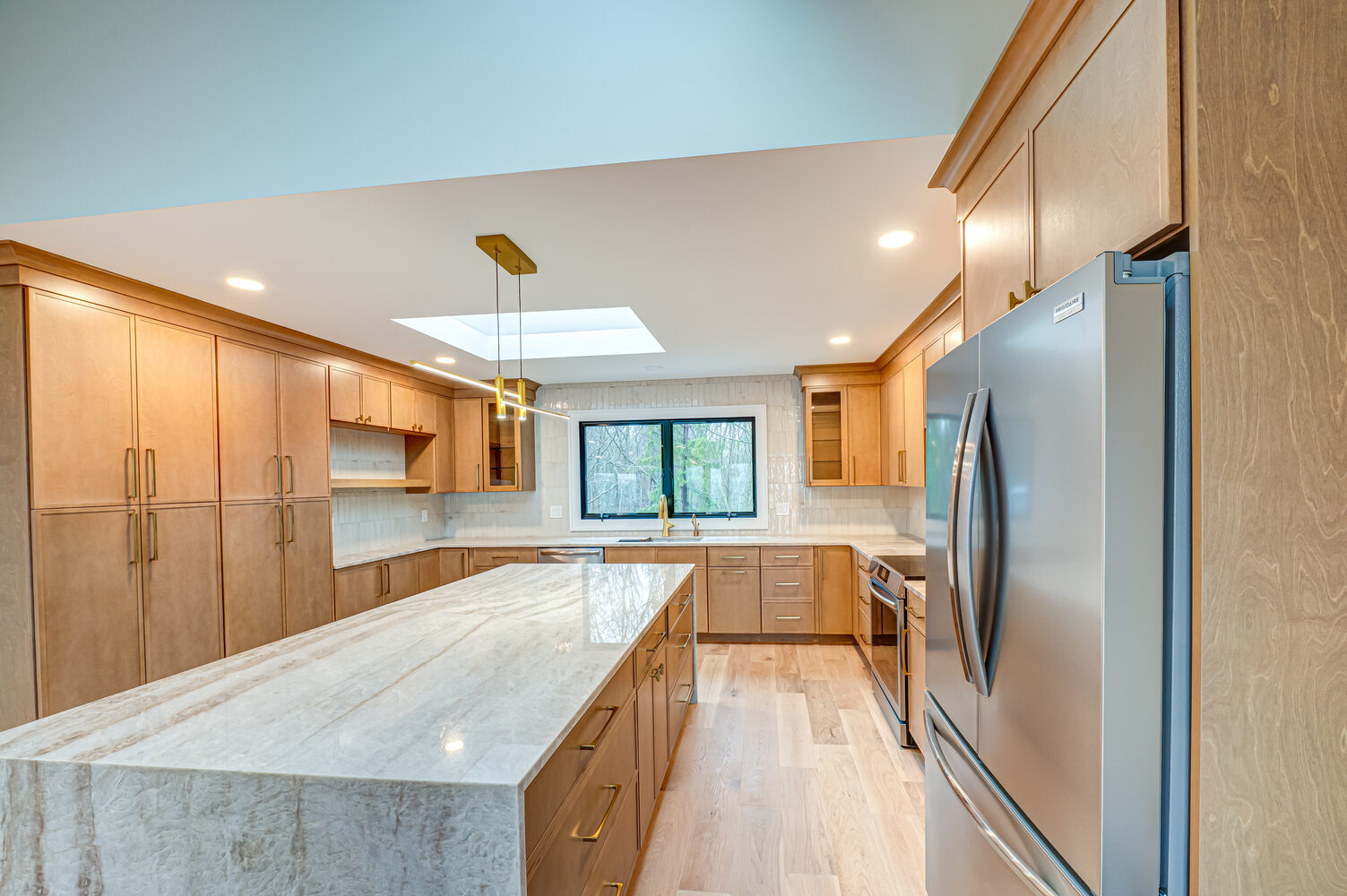 Marble island and wood cabinets in a custom kitchen by Long Island Creative Contracting in Miller Place, NY