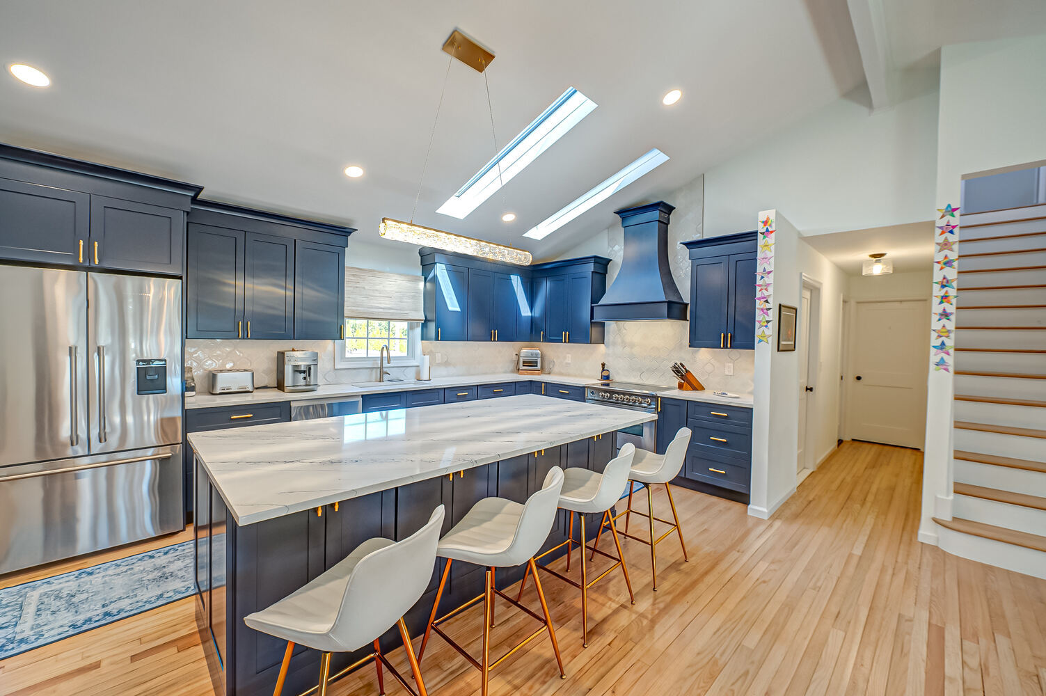 Spacious kitchen with navy cabinets and marble island in a custom home by Long Island Creative Contracting, Inc. in Miller Place, NY