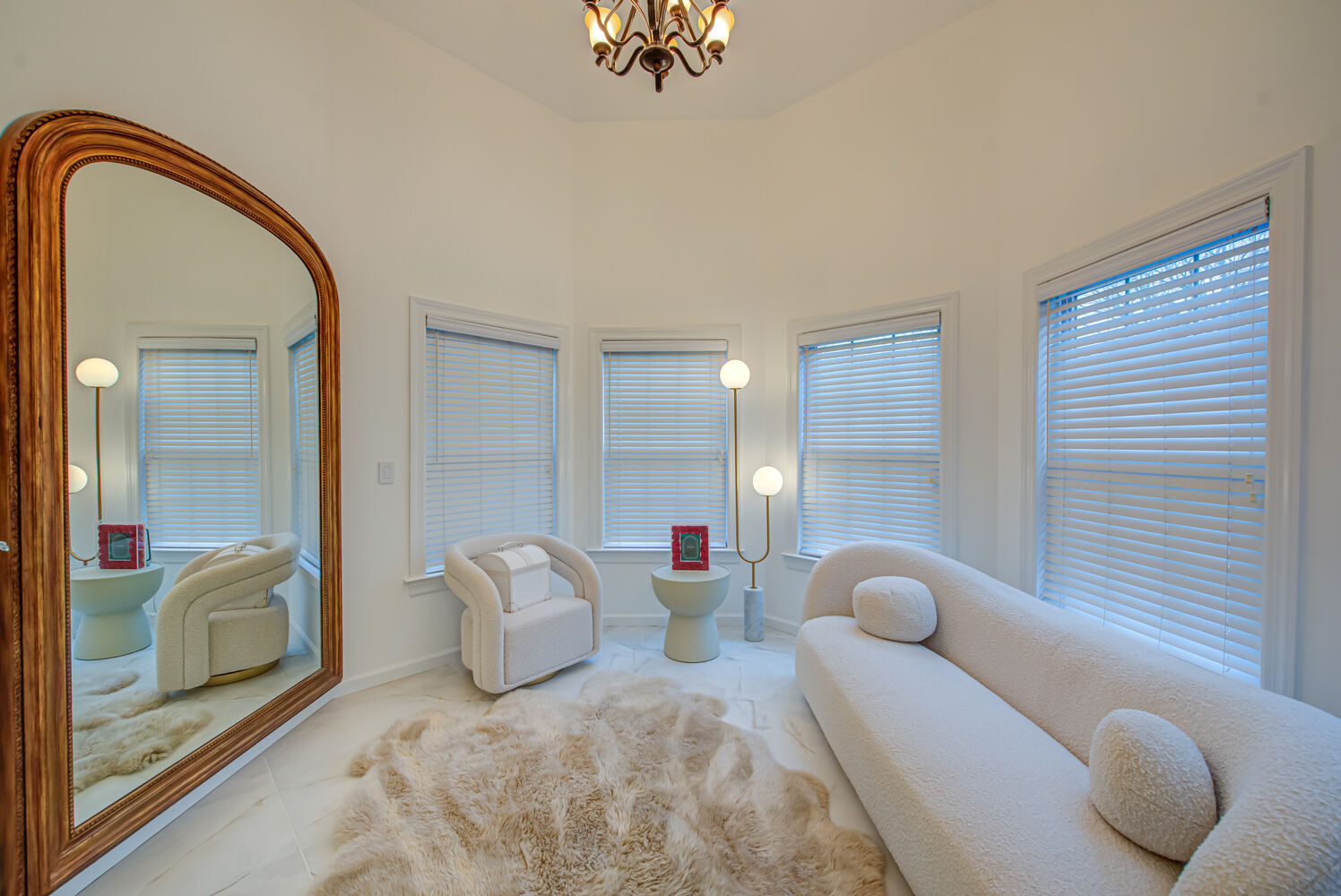 Cozy white sitting room with fur rug and arched mirror in Three Villages, NY by Long Island Creative Contracting, Inc