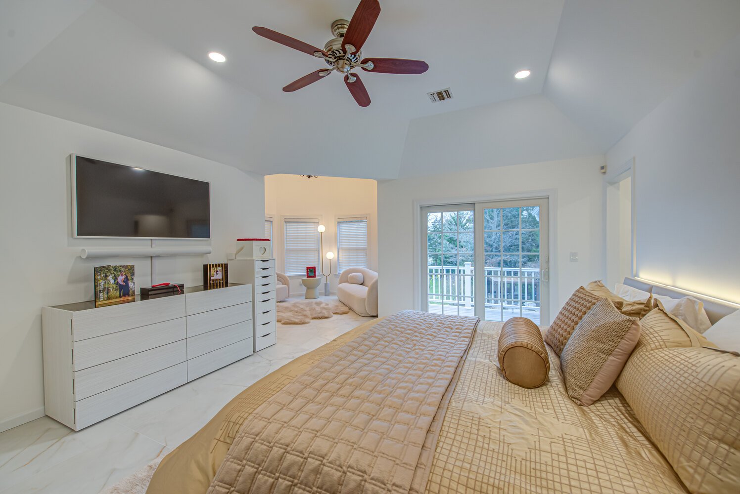 Luxurious master suite with flat-screen TV and connected sitting area by Long Island Creative Contracting, Inc. in Woodbury, NY