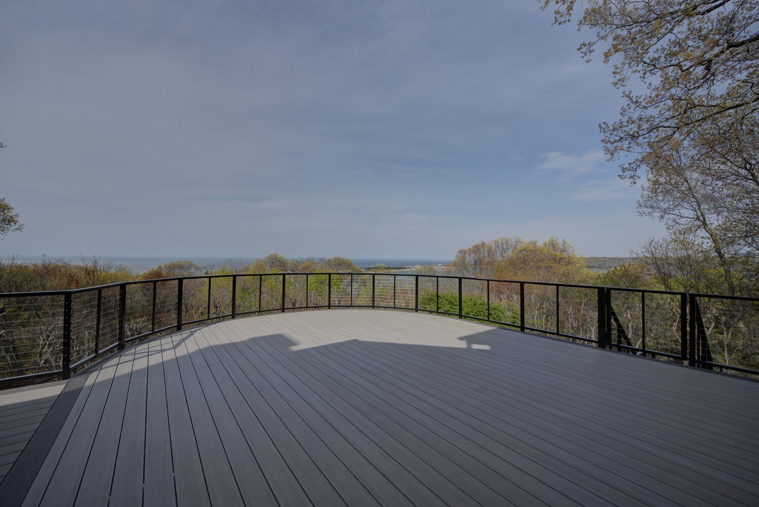 Modern custom home deck with metal railings and ocean backdrop in Remsenberg, NY