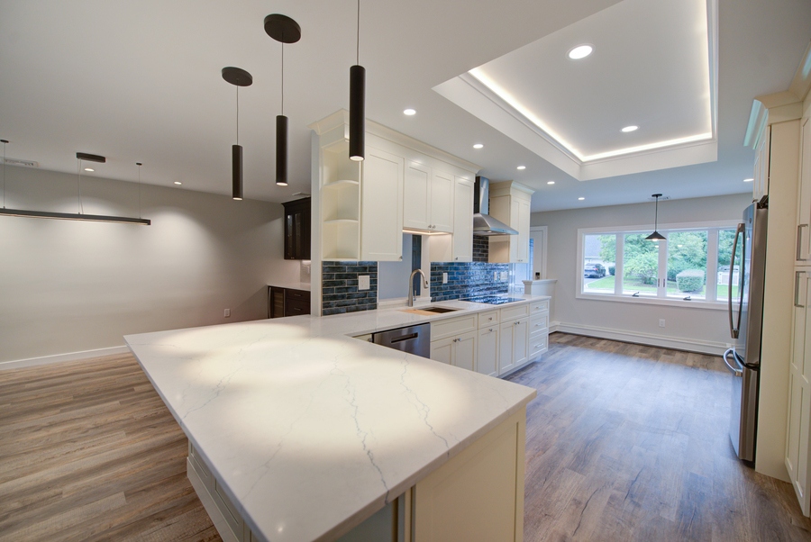 Open kitchen concept with marble island and pendant lighting in a Centereach, NY custom home