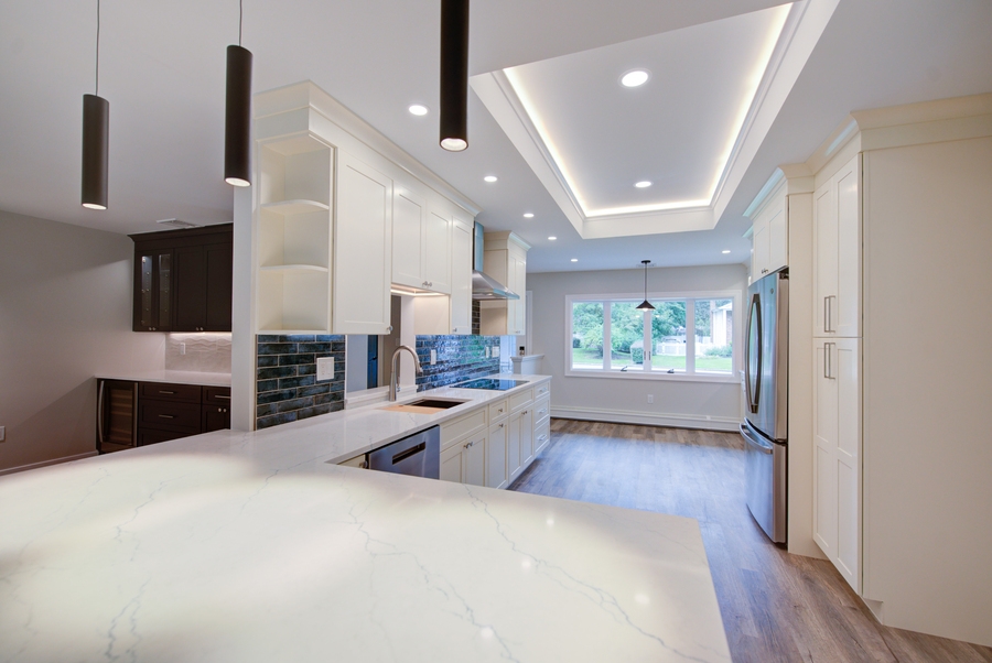 White shaker-style kitchen with statement lighting in a Suffolk County custom home by Long Island Creative Contracting, Inc