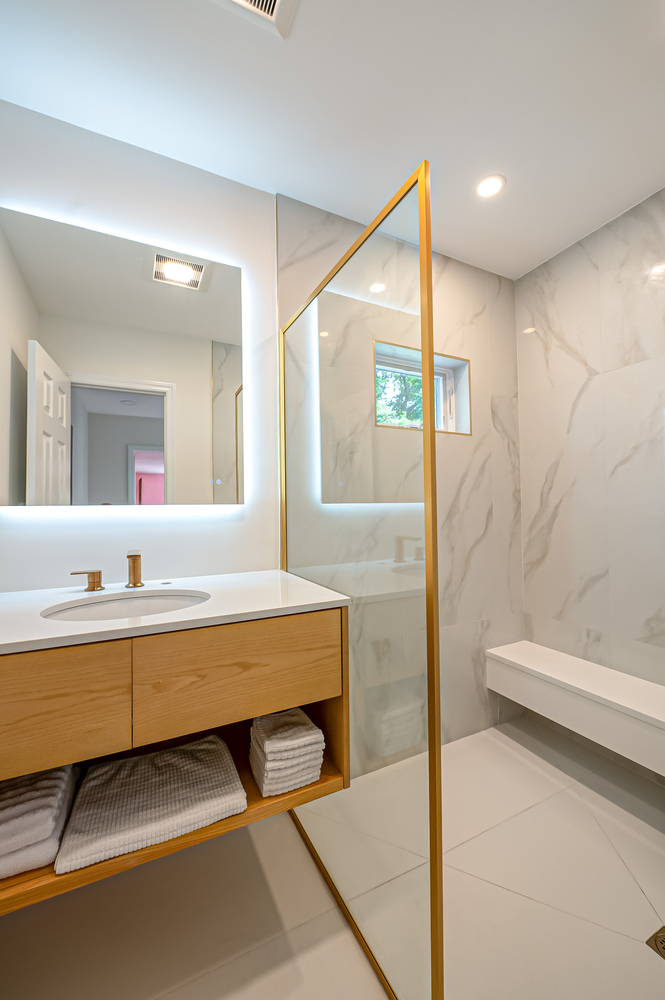 Luxury bathroom with glass partition and gold hardware in a Long Island Creative Contracting custom build in Port Jefferson Station, NY
