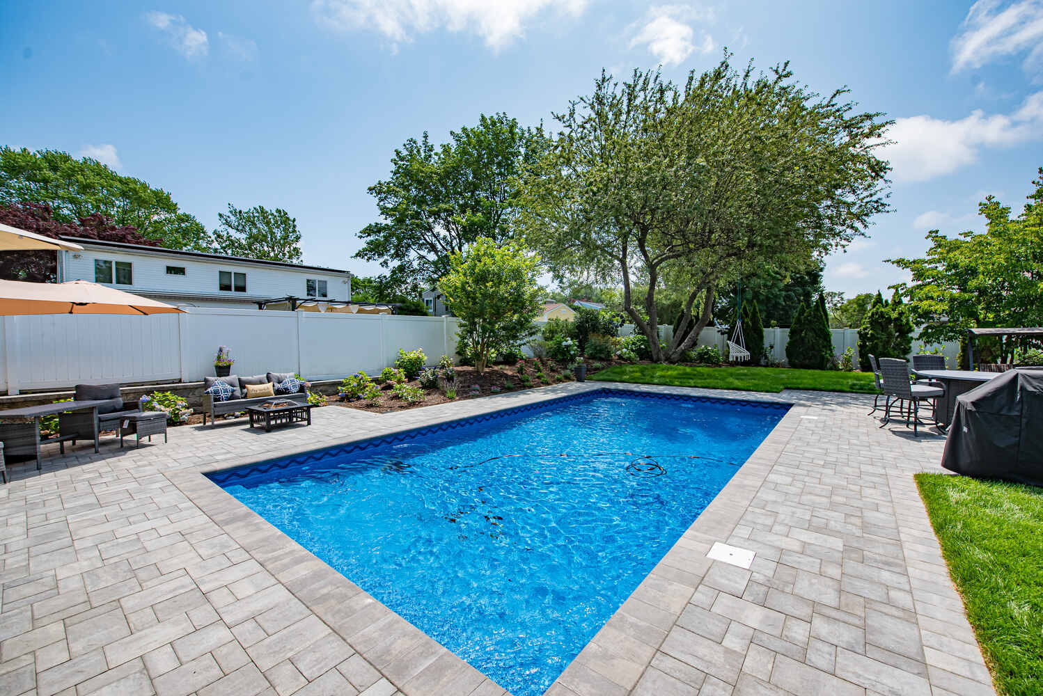 Sparkling custom pool with surrounding hardscape by Long Island Creative Contracting, Inc. in Suffolk County