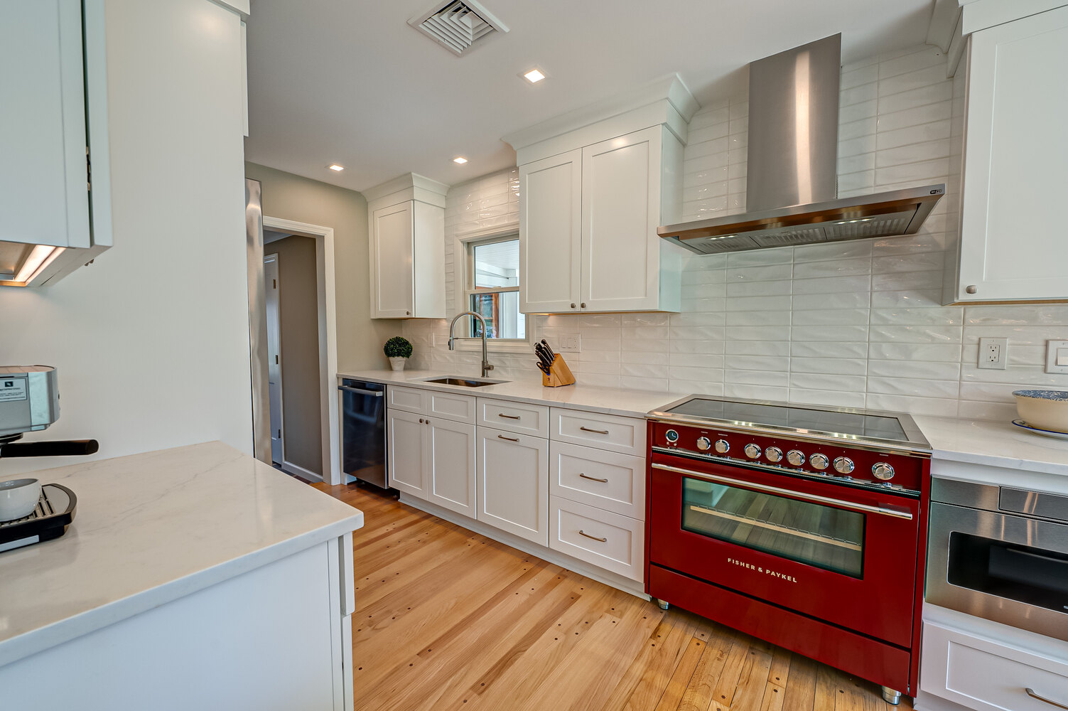 White kitchen cabinetry with standout red stove in a Suffolk County custom home by Long Island Creative Contracting, Inc